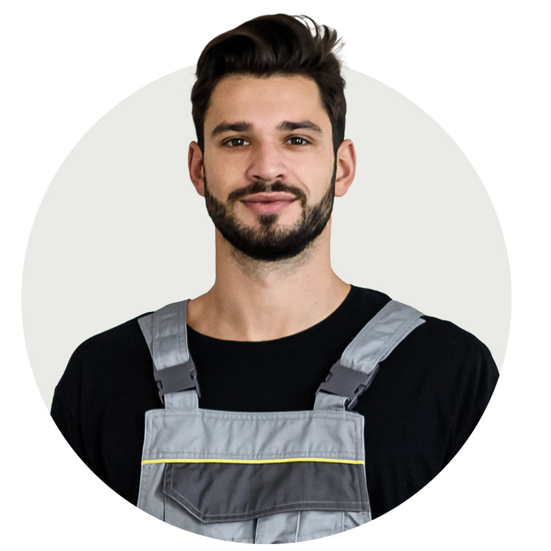Porträt eines jungen Schlüsseldienst-Mitarbeiters mit Latzhose – Teammitglied vom Aufsperrdienst Wien.