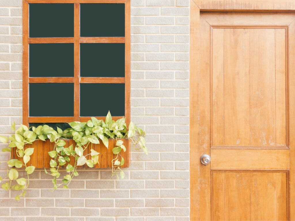 Holztür und Fenster mit Blumenkasten an einer Hausfassade – typische Eingangssituation für Einsätze vom Aufsperrdienst Wien.